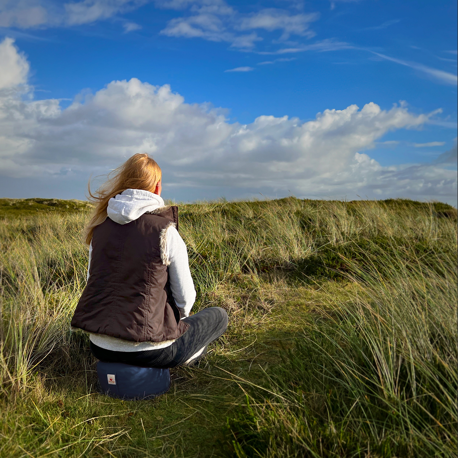 Mit dem Meditationskissen am Strand die Natur genießen.